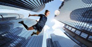 photo studio shot of girl footballer flying across cityscape